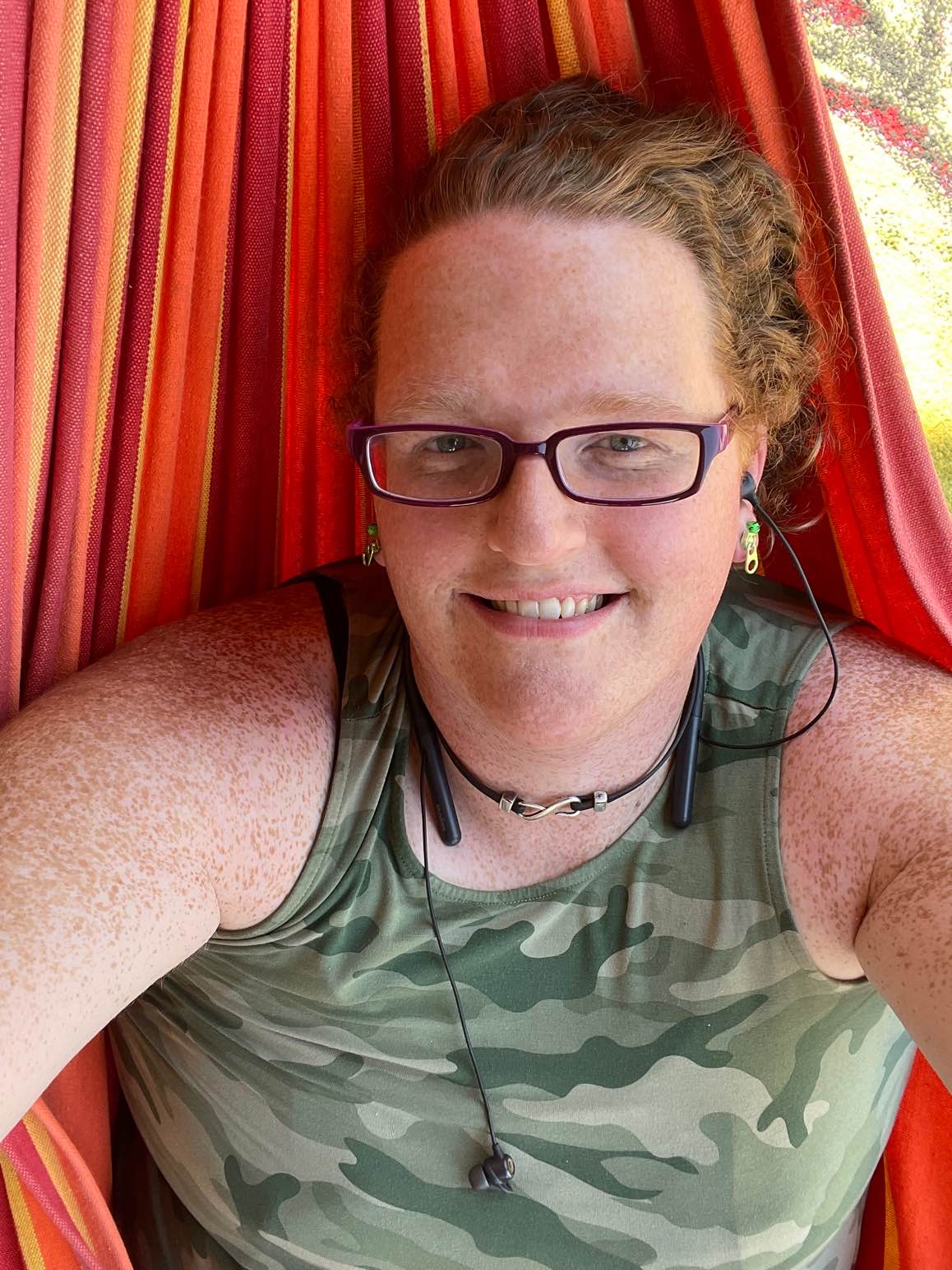 A picture of a woman lying in a hammock smiling at the camera